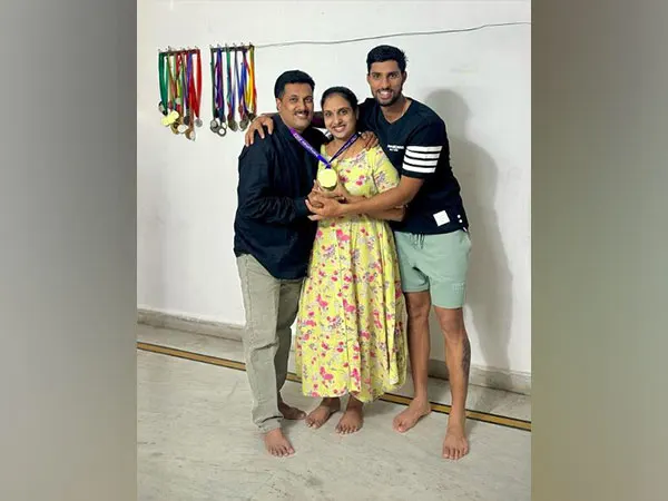 Tilak Varma posing with his father and mother while they hold a gold medal at their family home.