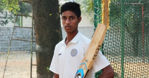 Young Tilak Varma holding a cricket bat beside practice nets during his early training years in Hyderabad.